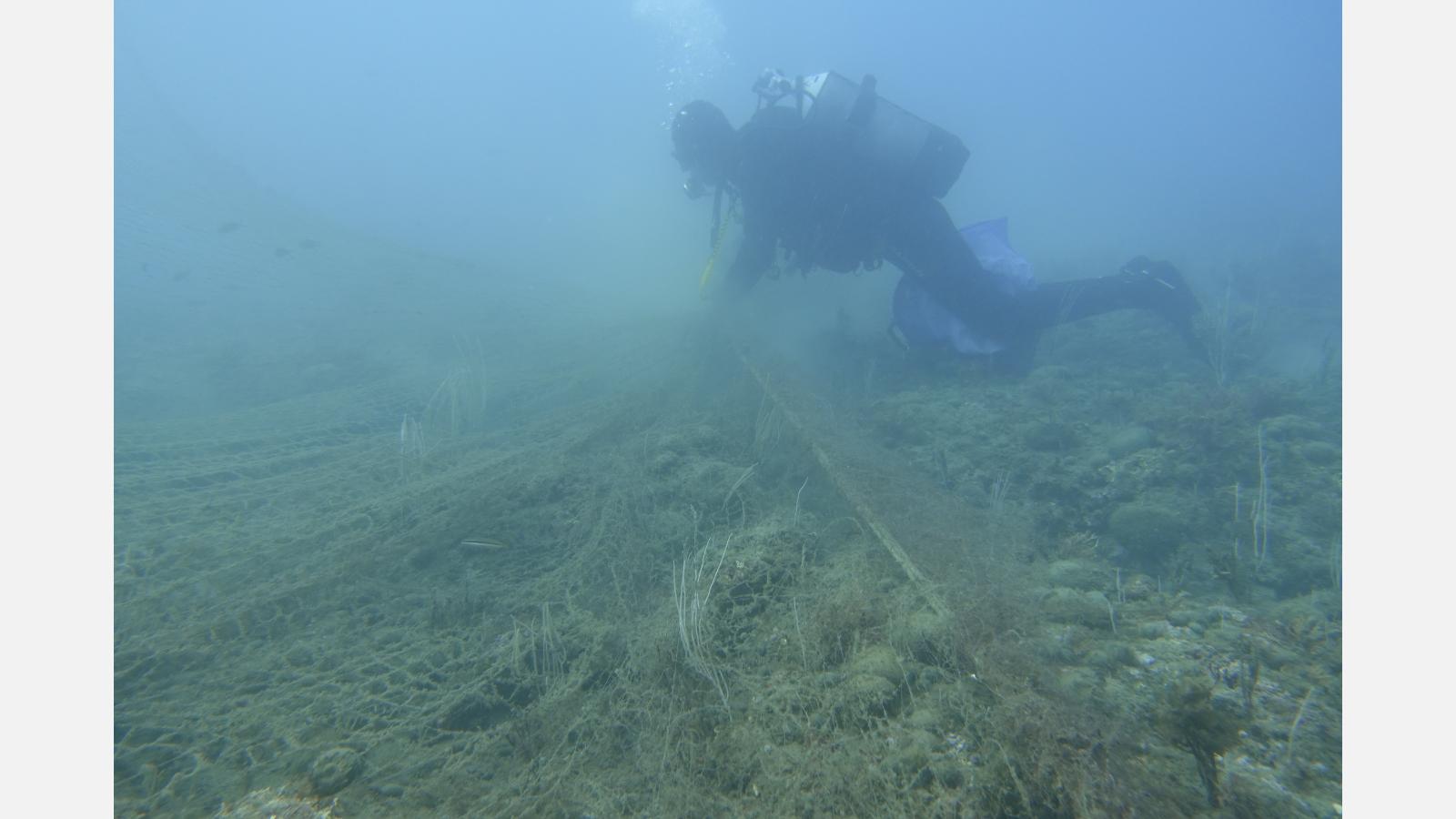 Plongeur travaillant à décoincer le filet pris dans la roche